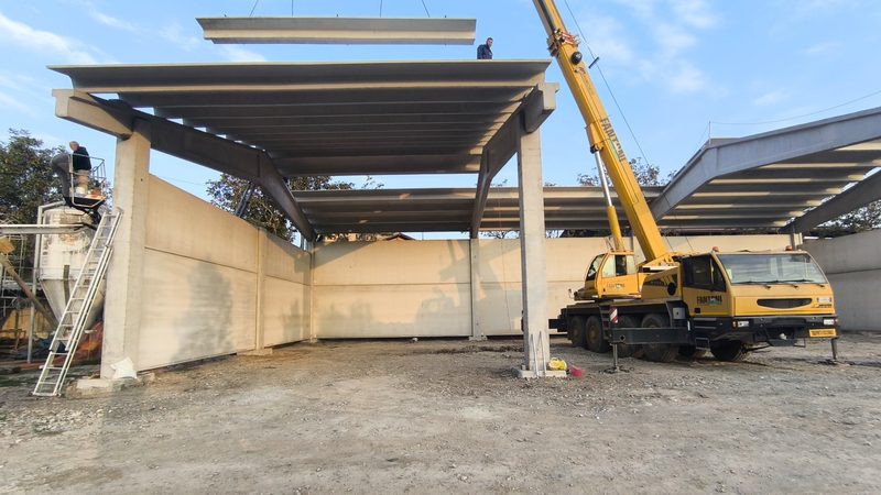 Montaggio con autogru di tegoli di copertura su struttura prefabbricata in cemento armato.